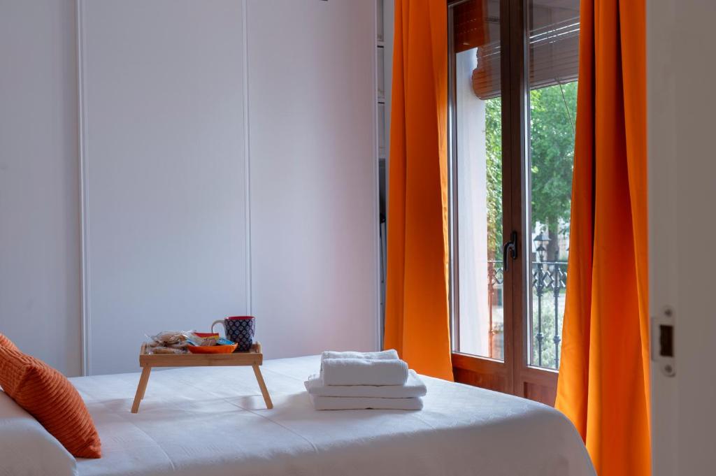 a bedroom with an orange curtain and a bed with a table at Casa Naranjo - Plaza Mayor Almagro in Almagro