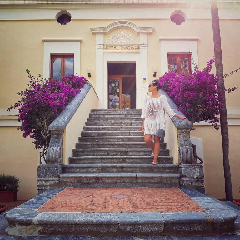 a girl standing on the stairs of a building at Hotel Palazzo Ducale in Diamante