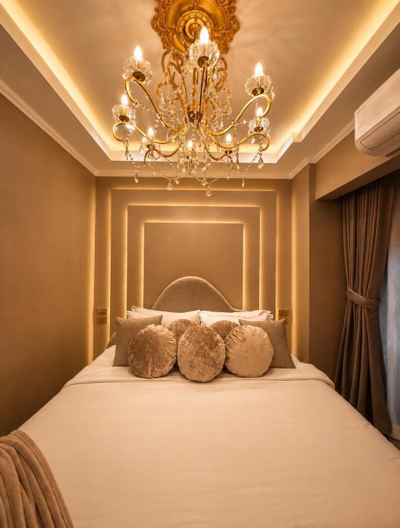 a bedroom with a bed with a chandelier at City View at The Gramercy Residences in Makati