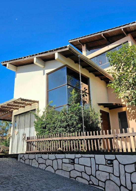 a house with a stone fence in front of it at Casa da Flor Guest House – Praia Grande – Beto Carrero in Penha