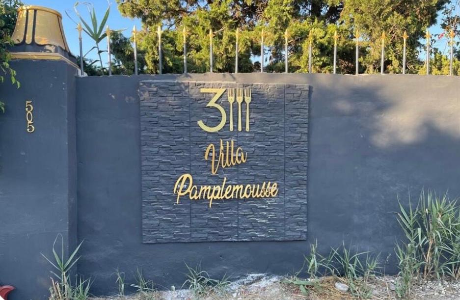 a sign on a wall in front of a building at Villa pamplemousse in Banī ‘Aţāʼ