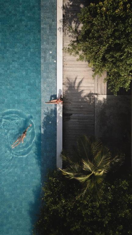 two people swimming in the water in a swimming pool at SABAI Beach Hotel in Barú