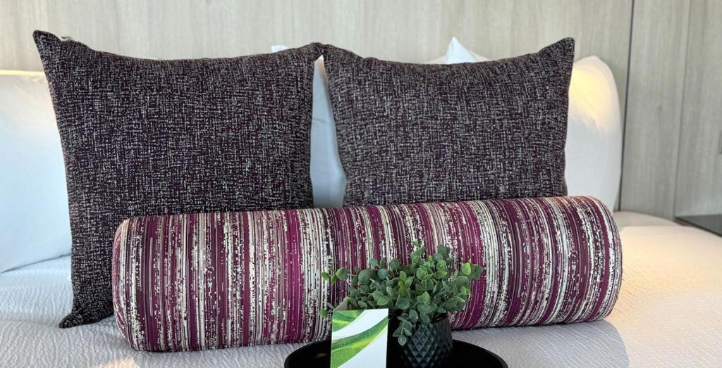 two pillows and a vase with a plant on a bed at Coast Red Deer Hotel in Red Deer