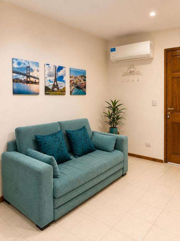 a blue couch in a living room with paintings on the wall at Alto Belgrano II in Mendoza