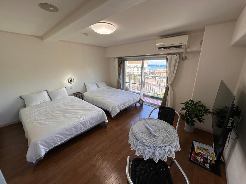 a room with two beds and a table and a window at Prince Plage OKINAWA 6F in Fuzuchi
