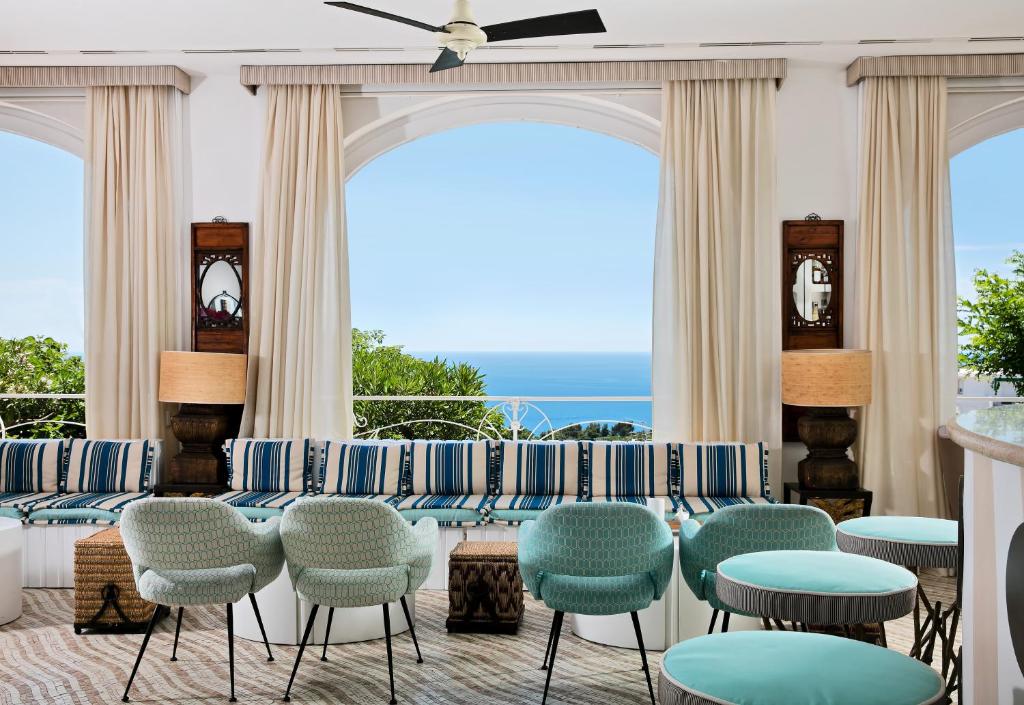 a room with chairs and tables and a view of the ocean at Capri Tiberio Palace - The Leading Hotels of the World in Capri