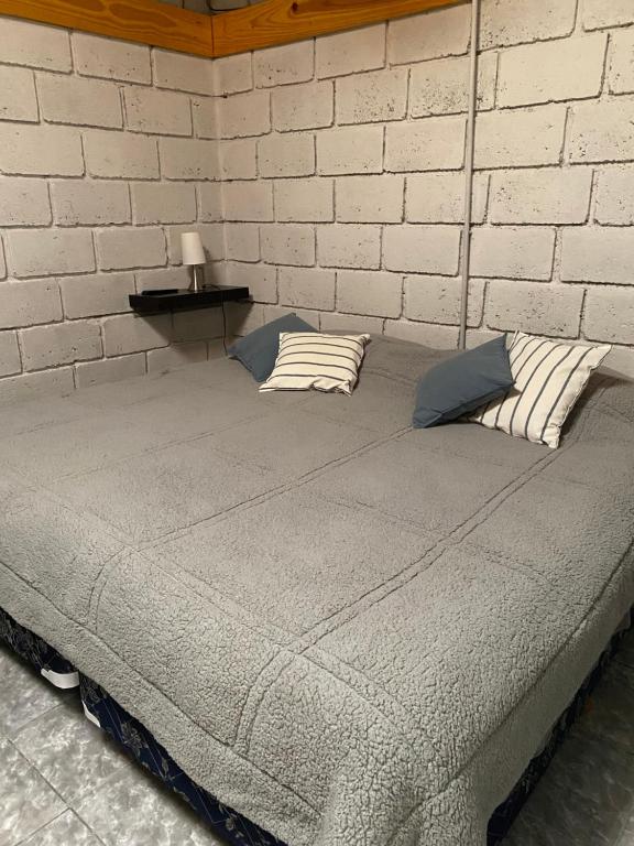 a bed in a room with a brick wall at Los Duraznillos in Los Antiguos