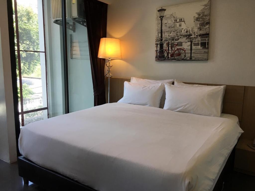 a large white bed in a room with a window at Marigold Ramkhamhaeng in Bangkok