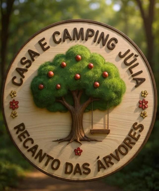 a sign for a camping village with a tree on it at Abrigo e Camping Recanto das Arvores in Itamonte