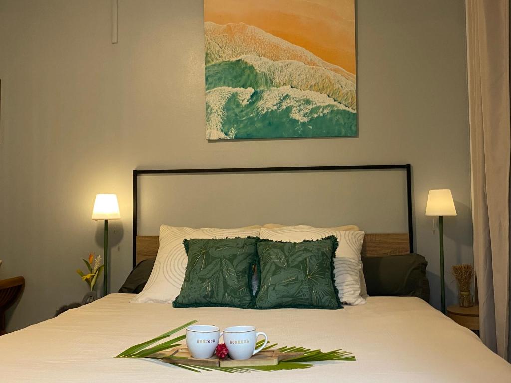 a bedroom with a bed with two cups on it at L'Isménia, L'écrin Zen in Le Gosier