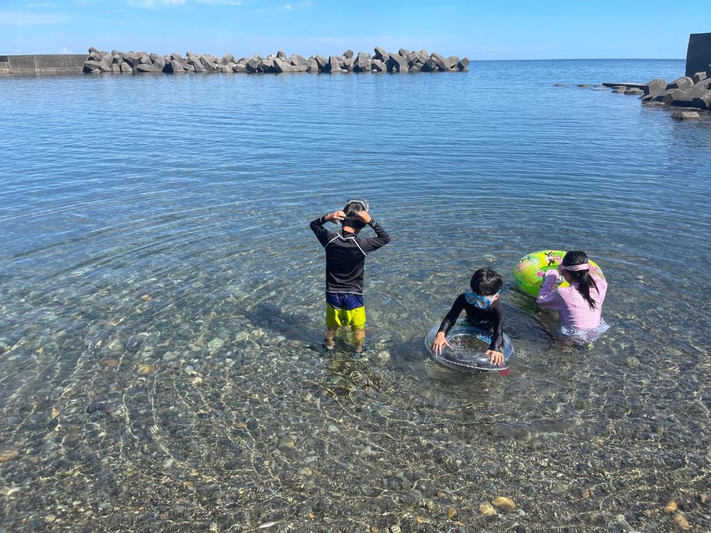 a group of three people standing in the water at Seaside House Nagi in Itoigawa