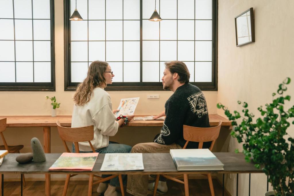 Ein Mann und eine Frau sitzen an einem Tisch und unterhalten sich. in der Unterkunft Hagi micro hotel in Gero