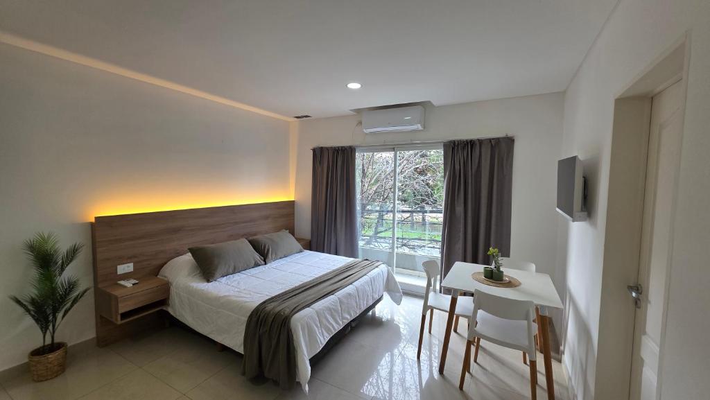 a bedroom with a bed and a table and a window at Aparts Magallanes in Pilar