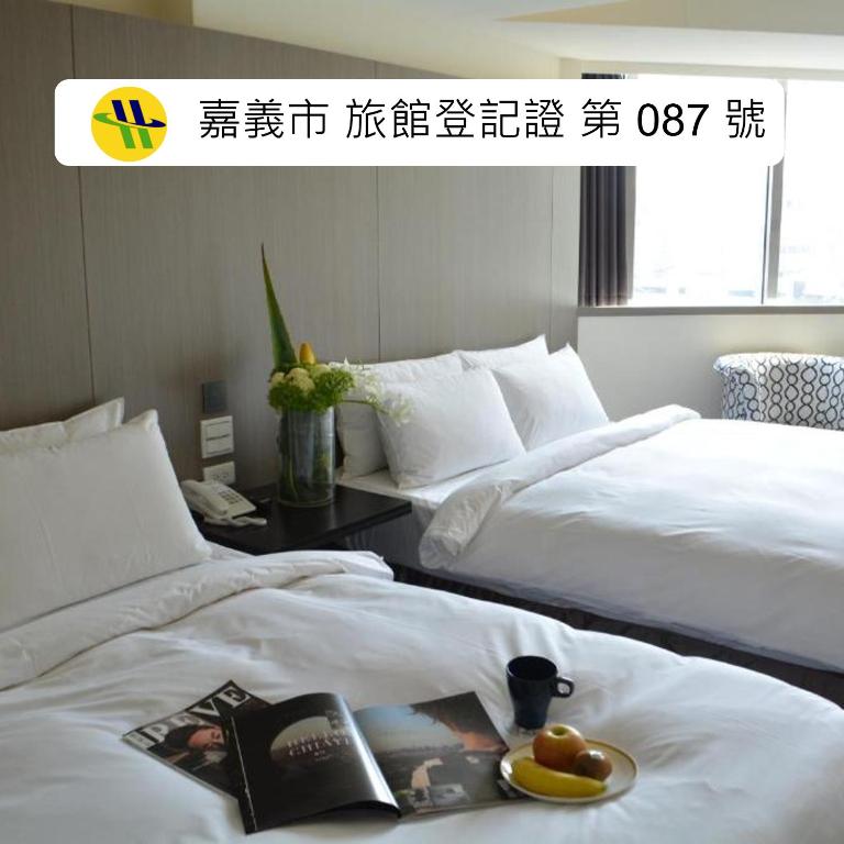 a hotel room with two beds with a plate of fruit at de rěve Express Hotel in Chiayi City