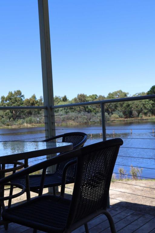 a table and chairs on a porch with a view of a river at Beaufort Lake Caravan Park in Beaufort
