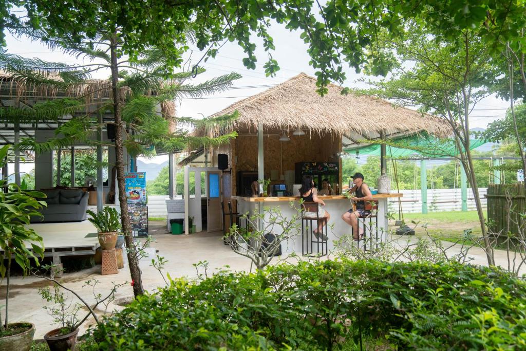 a woman sitting at a bar in front of a hut at Butterfly Resort Hostel, Pai in Pai