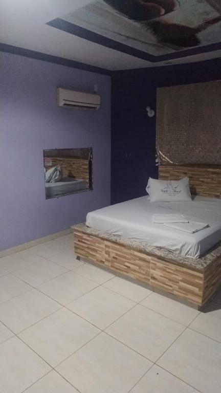 a bedroom with a bed with a wooden frame at Stilus pousada in Sinop