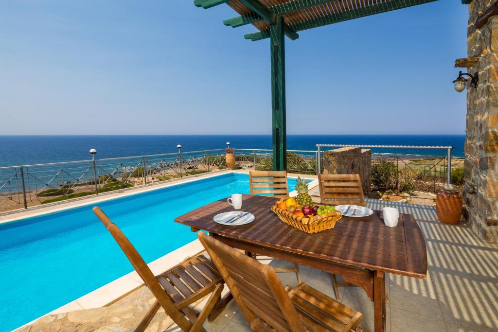 a table and chairs on a patio with a view of the ocean at Elafonissi Villa with Amazing Sunset Views & Private Pool near Elafonissi in AmigdhalokeFálion