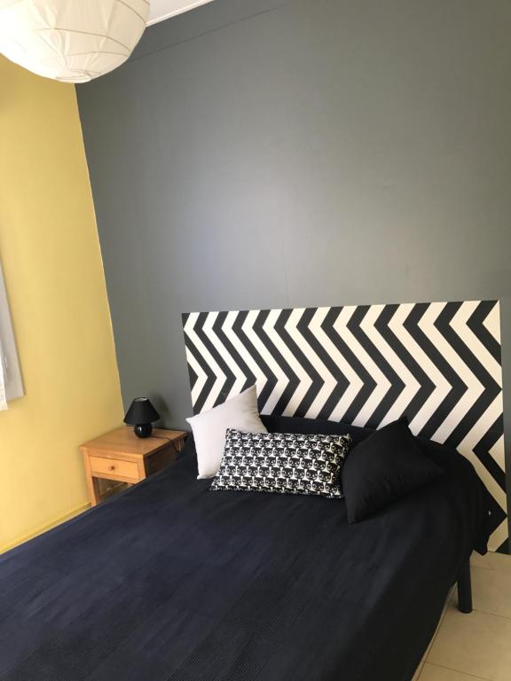 a bedroom with a black bed with a striped headboard at Gîtes de La Futaie in Sauzé-Vaussais