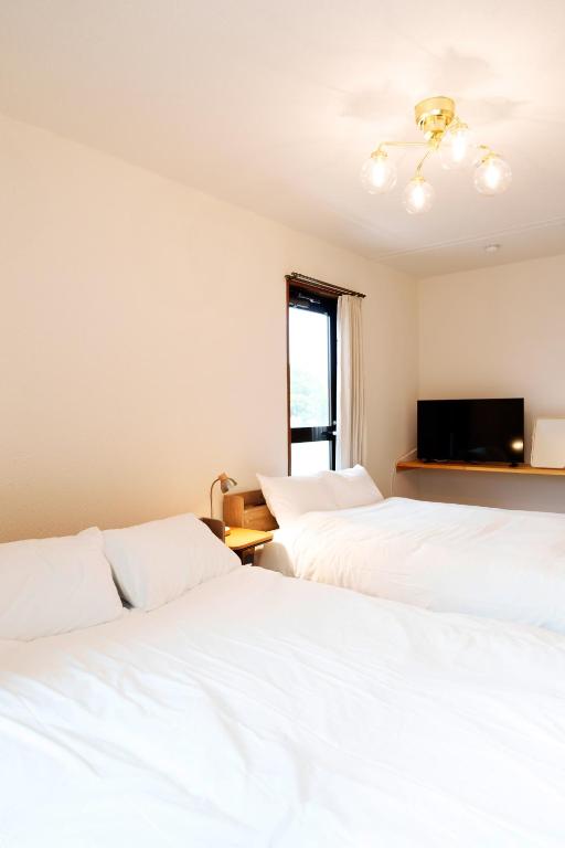 two white beds in a room with a tv at Haul Sakuramachi in Kumamoto