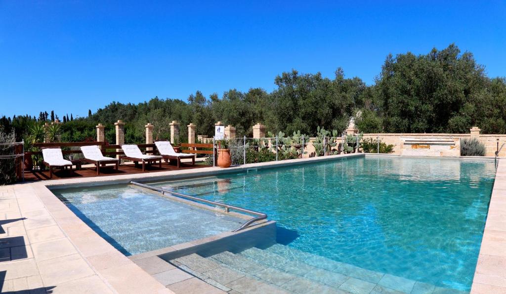 een groot zwembad met blauw water in een tuin bij Masseria L'Uliveto Agri Resort in Otranto
