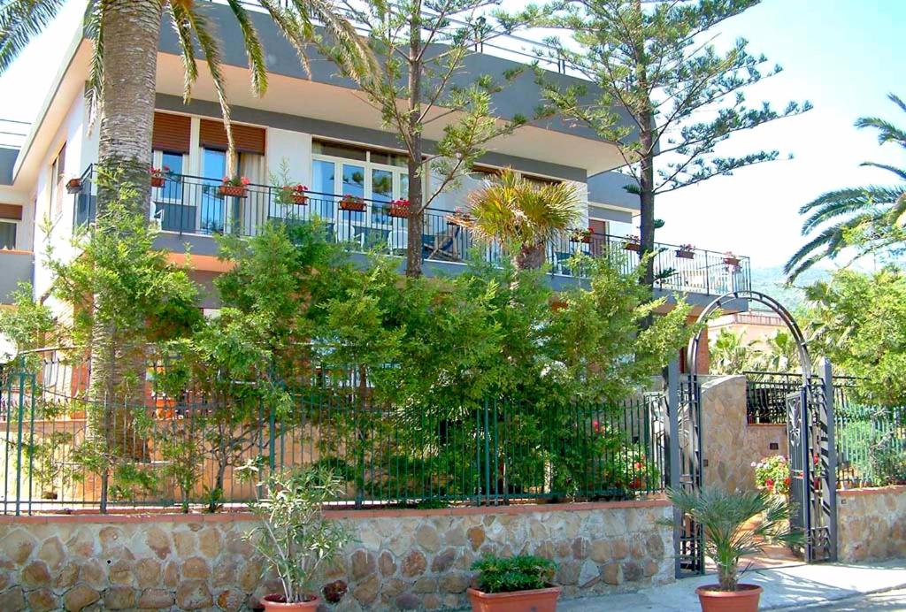 
a garden area with a building and trees at Villa Gaia Hotel in Cefalù
