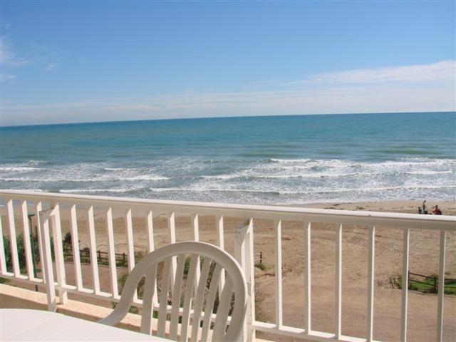 una silla blanca sentada en un balcón con vistas a la playa en Noria 305, en Alcossebre