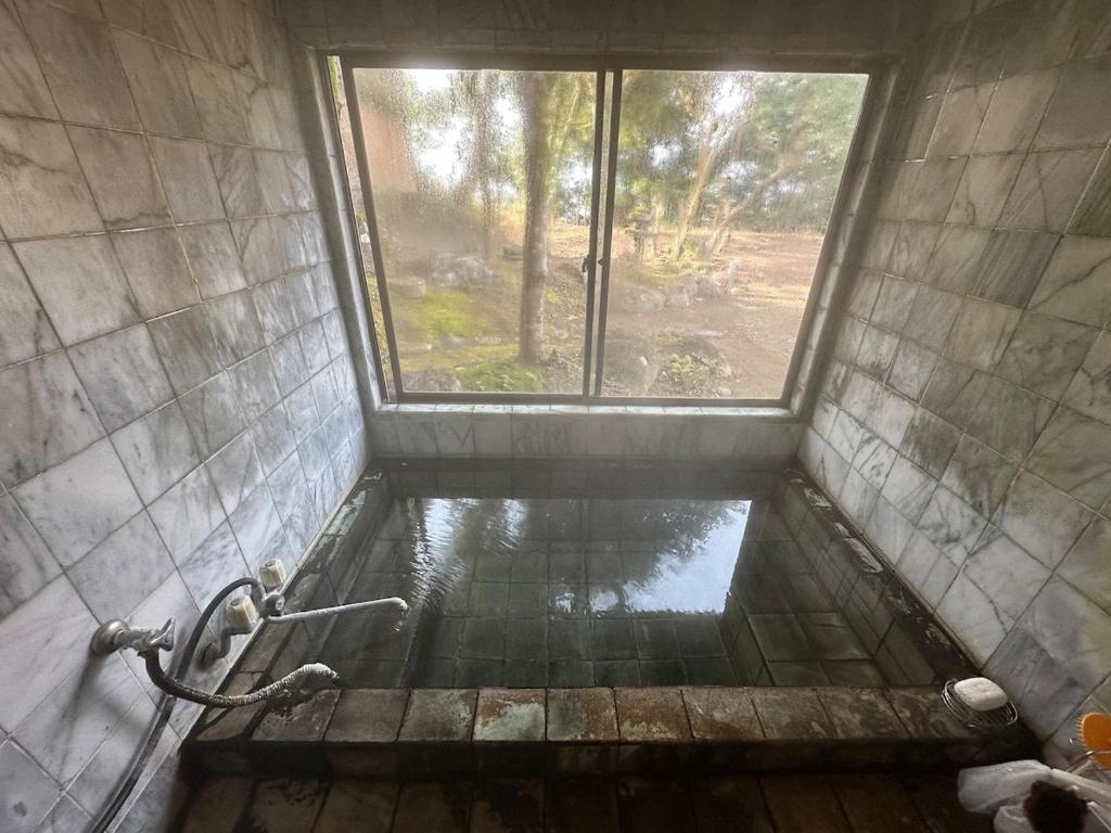 a bathroom with a shower with a window at 空港近くの温泉宿 翻車魚庵 in Kirishima
