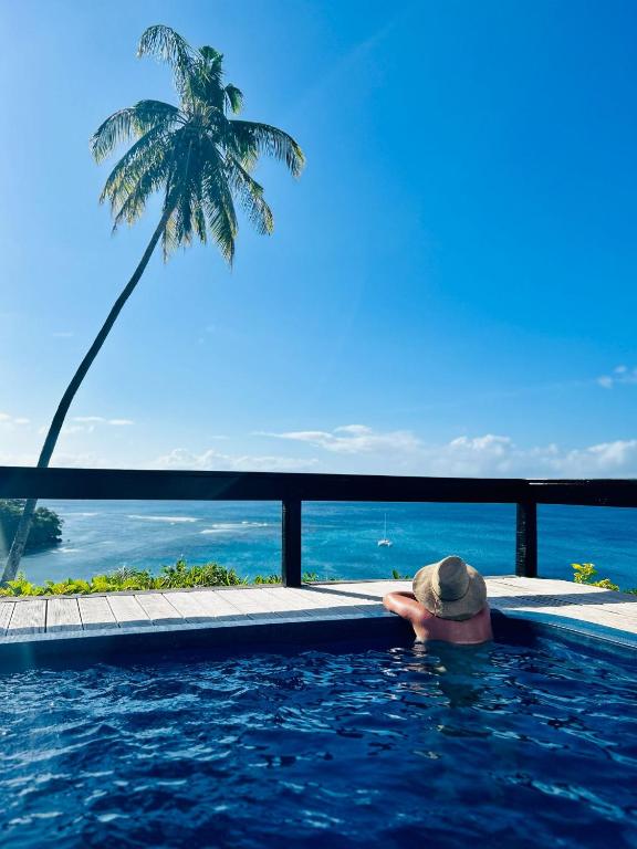 a person in a swimming pool next to a palm tree at Ucuilagi Resort in Matei