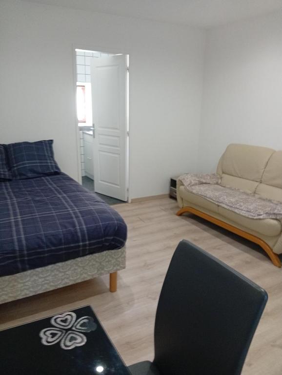 a bedroom with a bed and a couch at Petit studio in La Souterraine