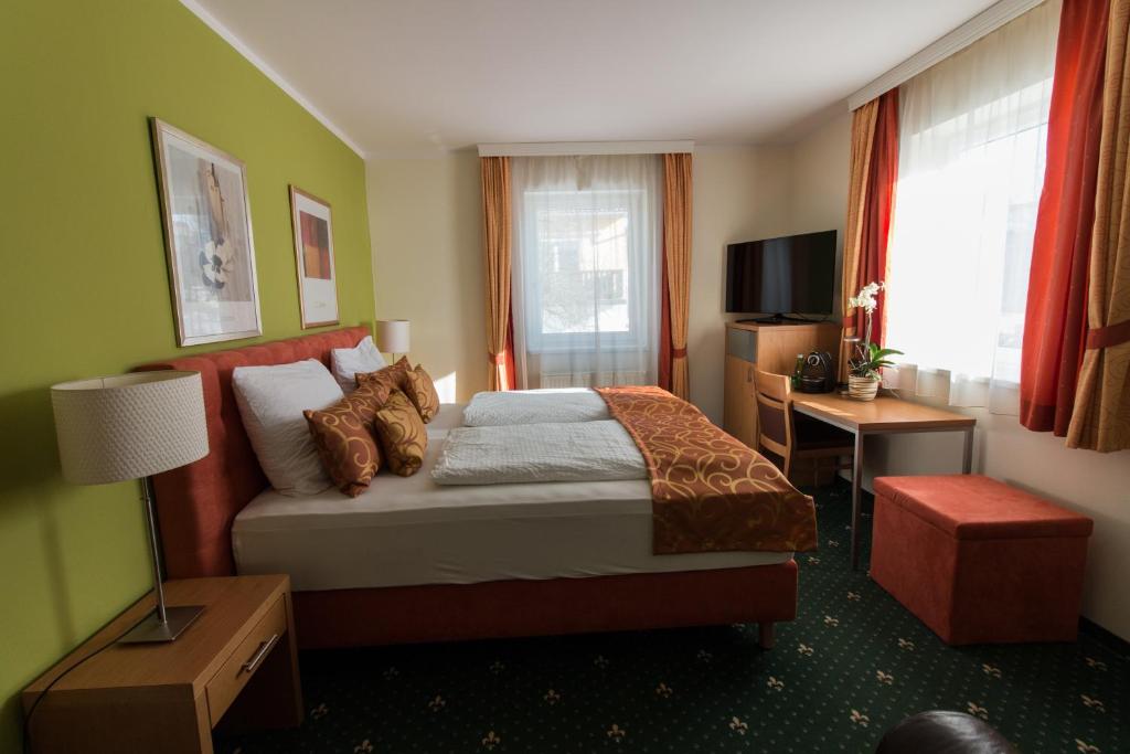 EngerwitzdorfにあるHotel Kreuzwirtのベッドとデスクが備わるホテルルームです。