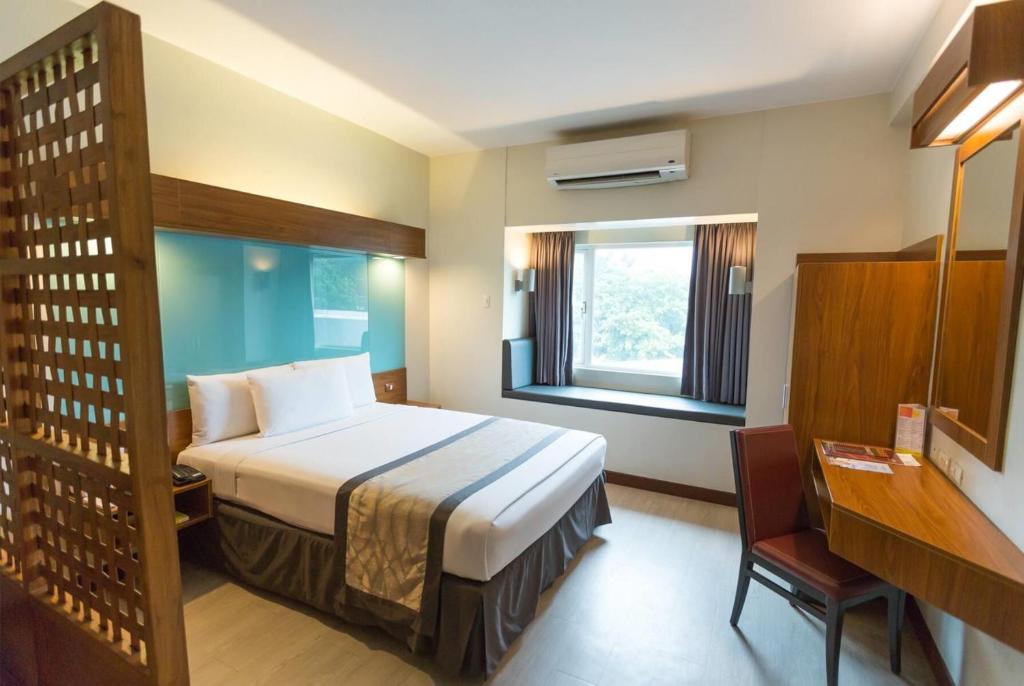 a hotel room with a bed and a window at Microtel by Wyndham UP Technohub in Manila