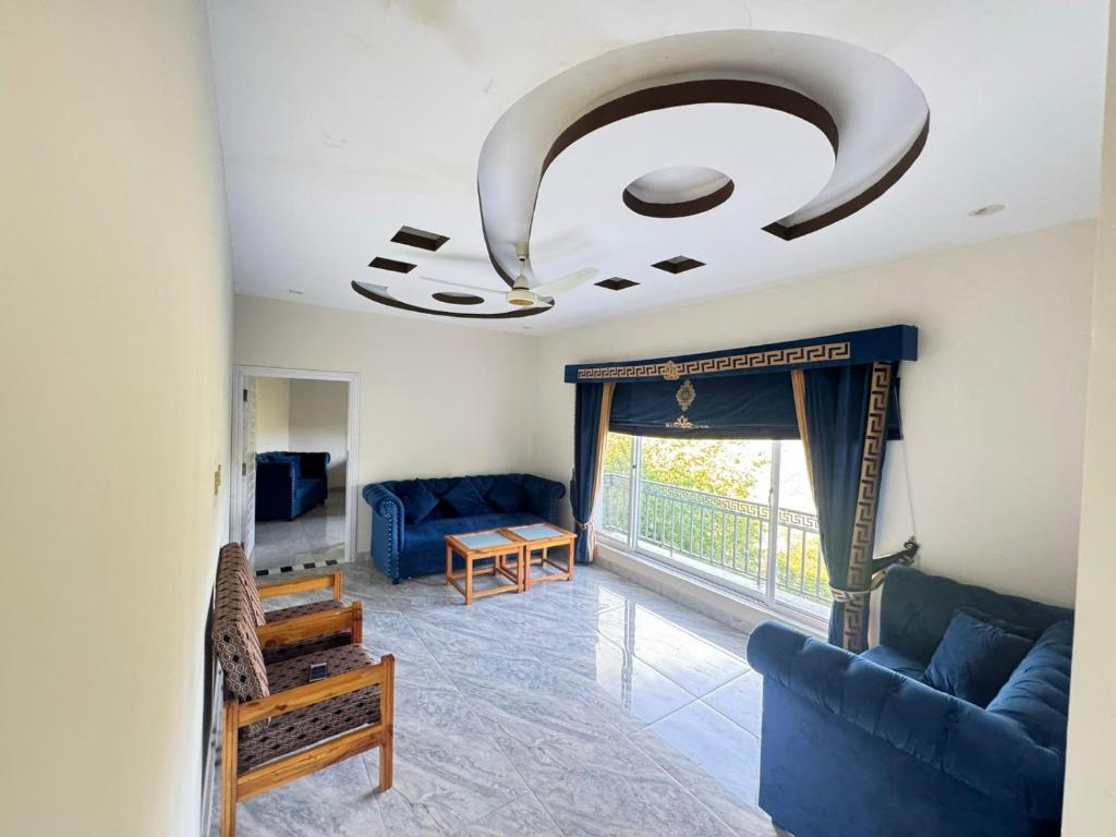a living room with blue furniture and a large window at EmberGuestHouse in Abbottabad