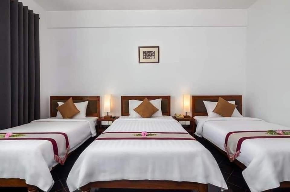 a hotel room with three beds with white sheets at Khemra Guesthouse in Kampot in Kampot