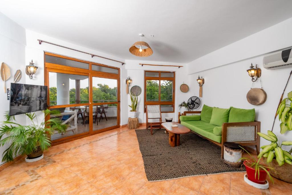 a living room with a green couch and a table at Hewani a bright & airy 1 BR apartment with an ocean view & pool in Kilifi