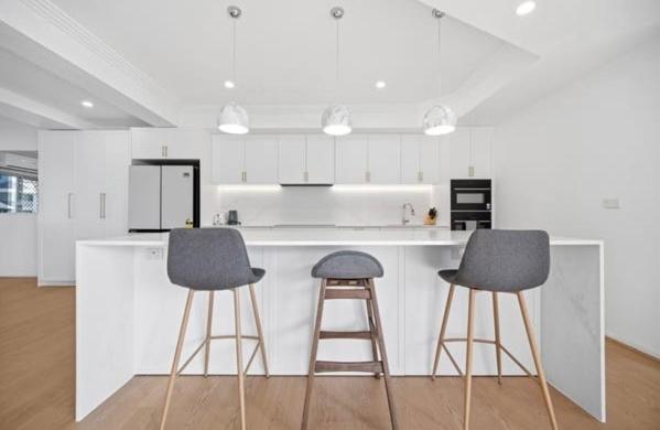 a kitchen with two stools and a counter with a refrigerator at Stunning Waterfront Escape in Gold Coast