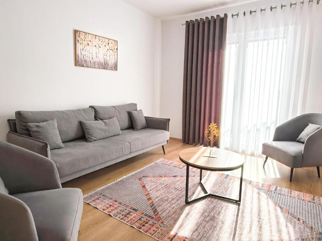 a living room with a couch and a table and chairs at Enjoy Shkodra Apartment in Shkodër
