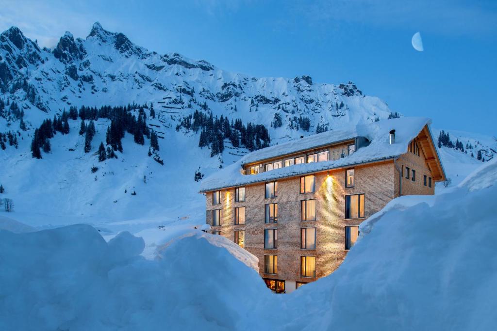 a building covered in snow with snow covered mountains at Ski Hotel Mondschein 1739 in Stuben am Arlberg