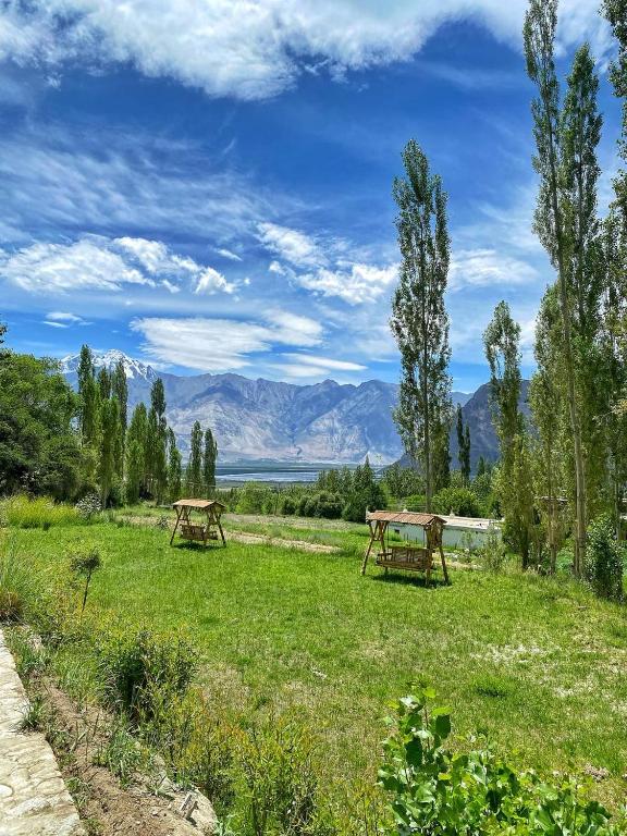 two picnic tables in a field with mountains in the background at Lharje Resort in Satti