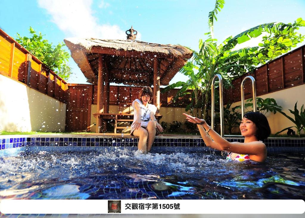 two women are sitting in a swimming pool at Howard Villa in Kenting