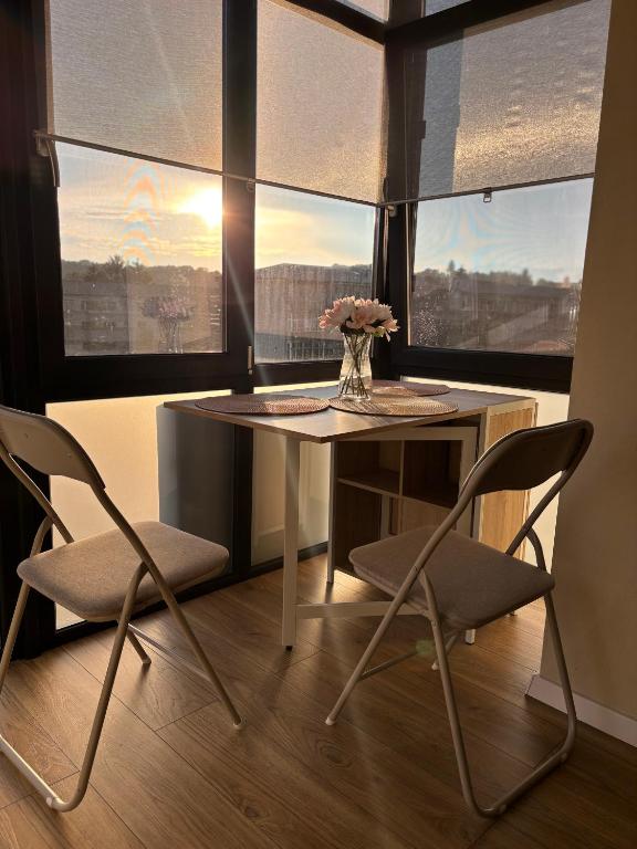 a table and two chairs in a room with windows at MOuntain View Apartment in Câmpulung