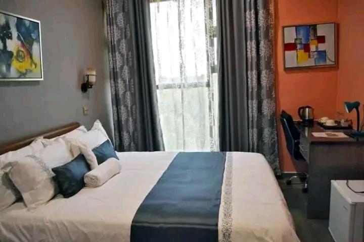 a bedroom with a bed and a desk and a window at Kanyi GuestHouse in Palatswe