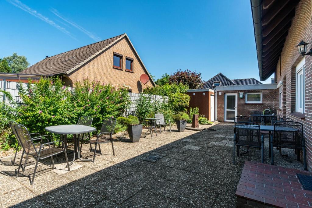a patio with tables and chairs next to a house at Haus Achtern Diek - Ferienwohnungen in Wangerland