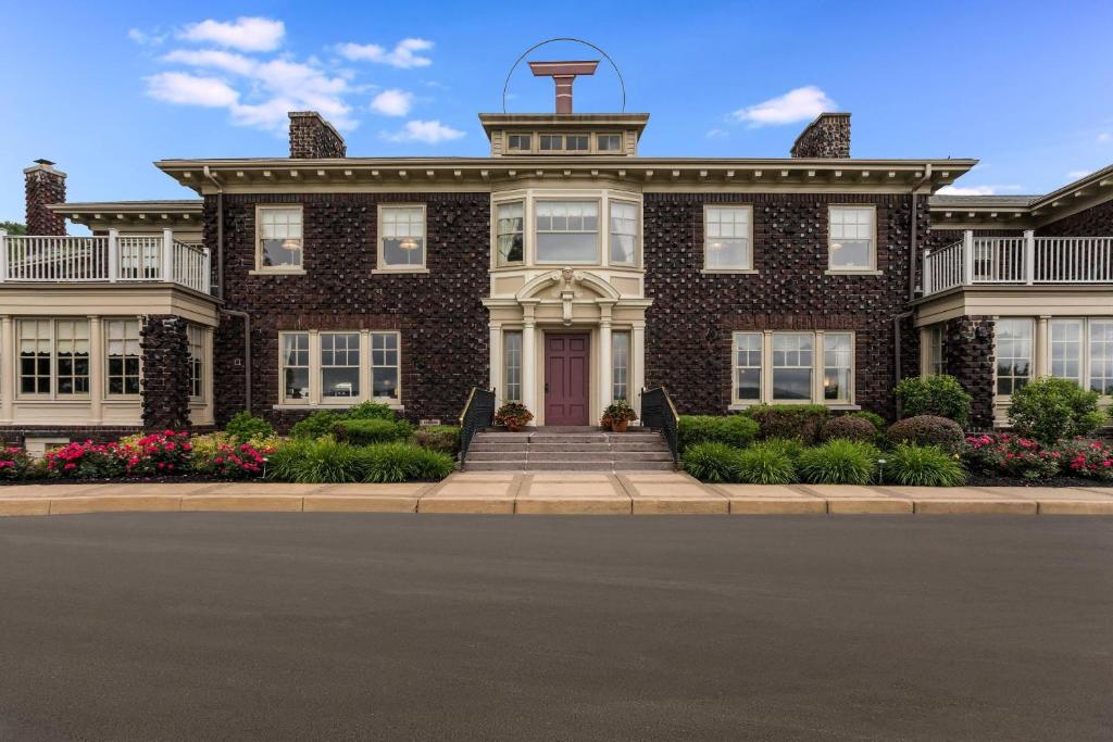 a large brick house with a clock tower on top at Traditions Hotel & Spa Johnson City - Binghamton, an Ascend Collection Hotel in Johnson City