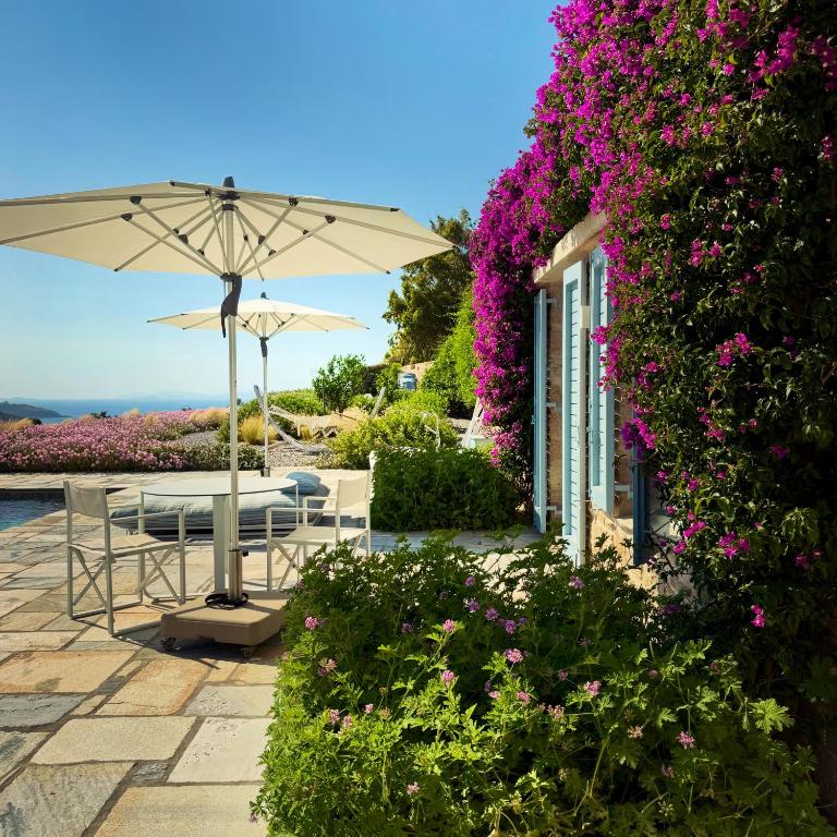 a patio with a table and an umbrella and flowers at Patmosphere Luxury Escape Adults-Only in Patmos