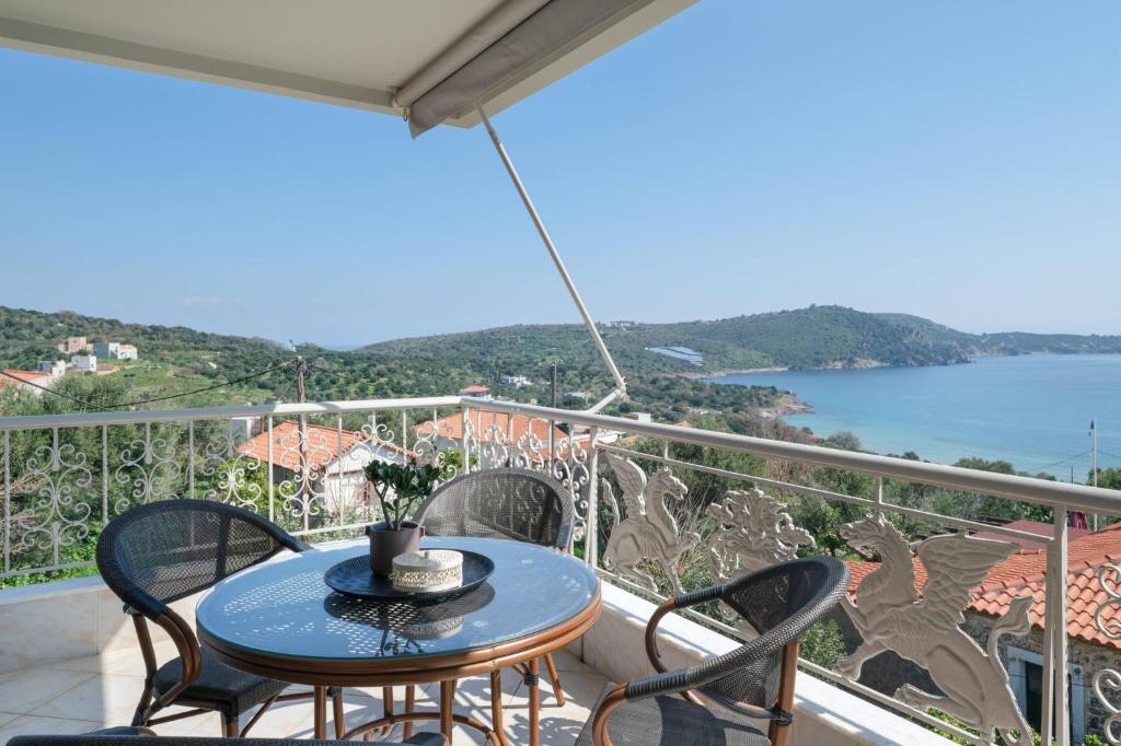 a table on a balcony with a view of the water at Panorama Apartments in Skoutari
