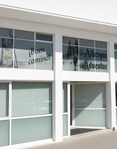 a white building with windows and signs on it at Albergue Adventus in Padrón