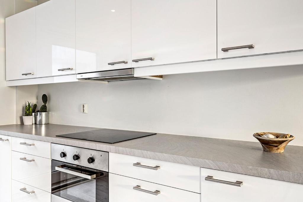 a kitchen with white cabinets and a counter top at Engen Apartment in Bergen