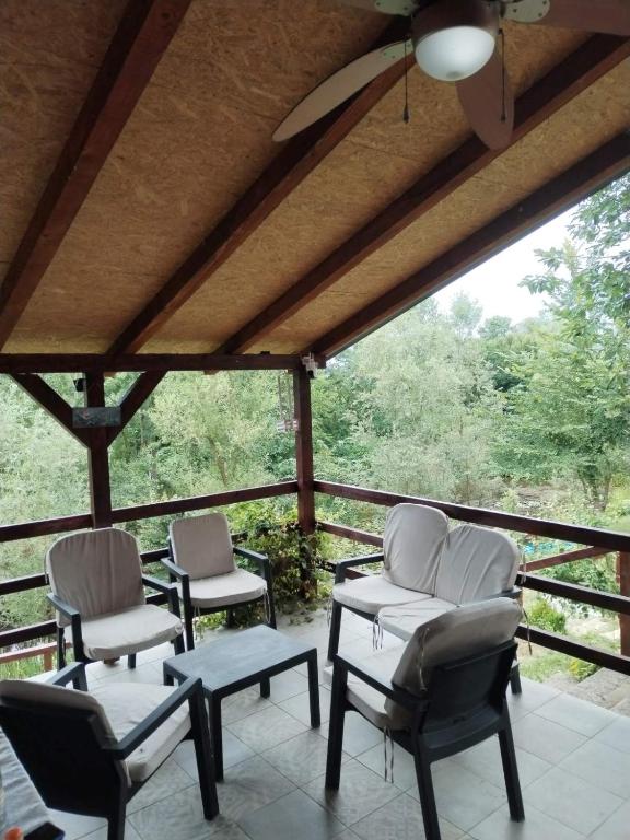 a porch with three chairs and a table and a ceiling at Vila Lokvanj in Gornja Vranjska