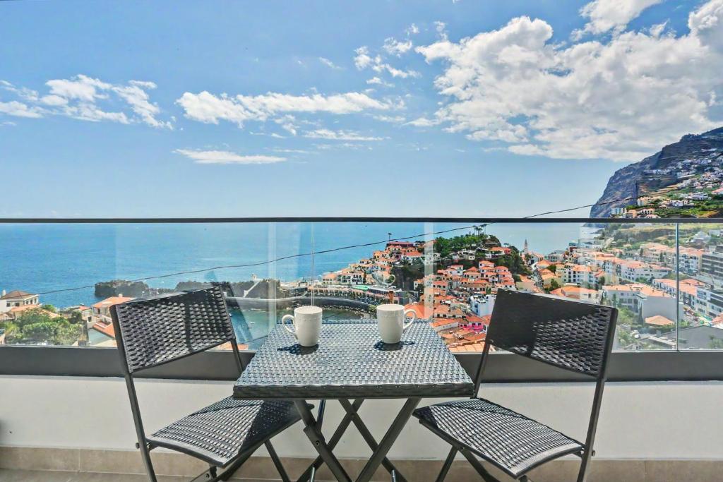 a table and chairs on a balcony with a view of the city at Lobo's House in Câmara de Lobos